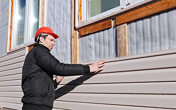 Contractor installing siding while protected with small business insurance in Raleigh, NC