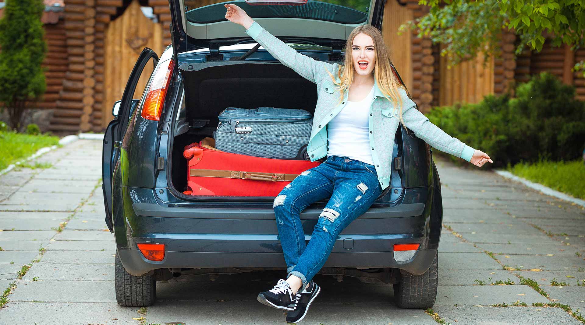 Lady Sitting on Back of Trunk of Car with Suitcases Loaded with Auto Insurance in Cary, NC