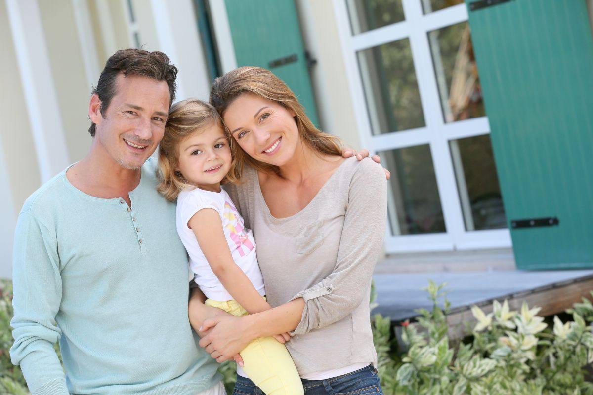 Portrait of Happy Family Standing in Front of House with Home Insurance in Durham, NC